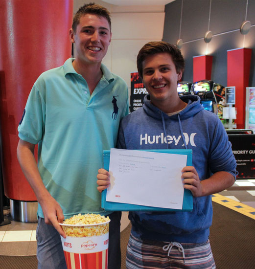 Hoyts customers holding a bucket of popcorn and a customer feedback form