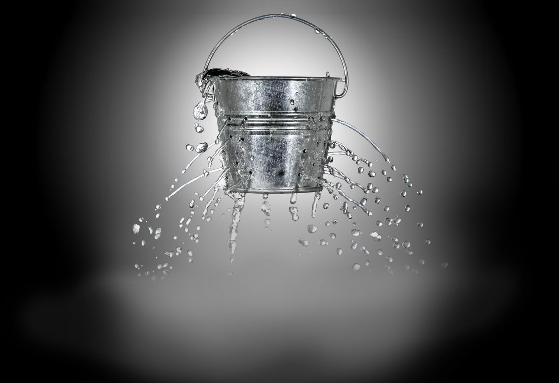 A bucket which is leaking due to many holes punctured in its metal.