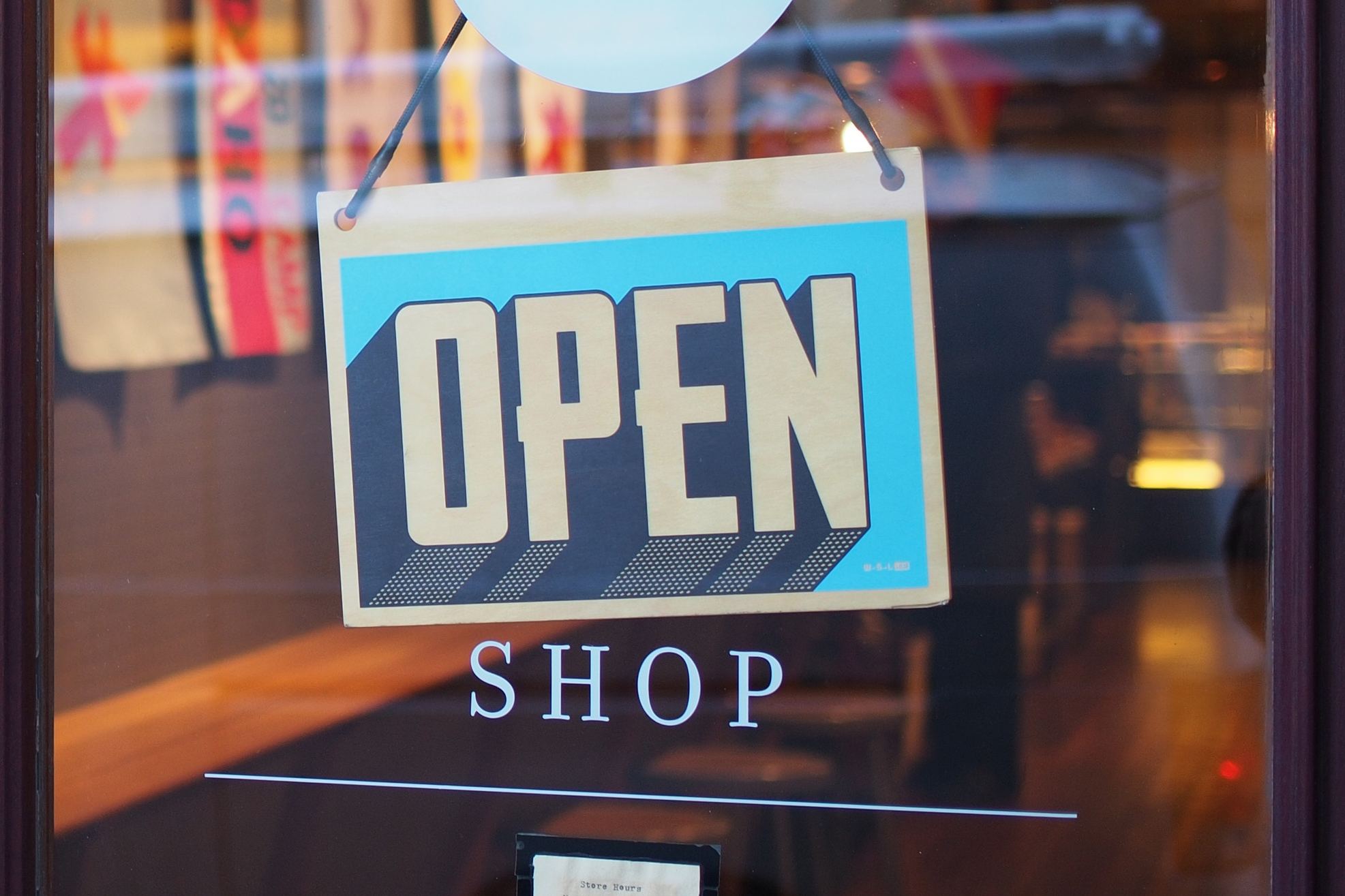 Open sign in a retail shop front window representing the creation of a remarkable retail shopping experience