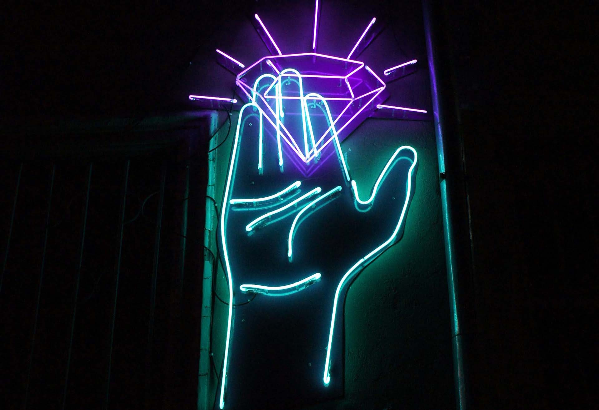 Neon sign of a hand capturing a diamond representing the brilliant basics