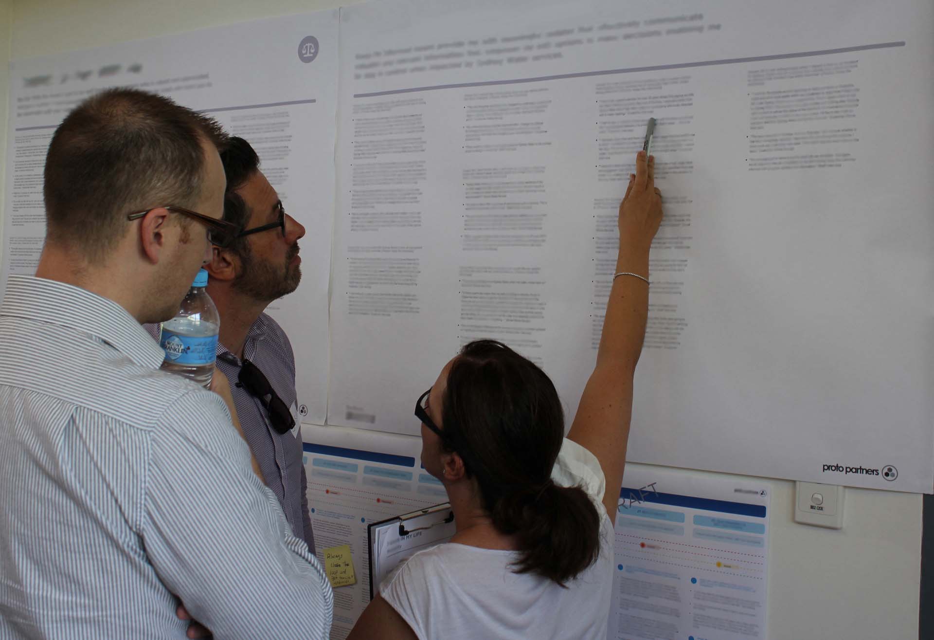 Proto experience designer pointing out CX information to two other designers