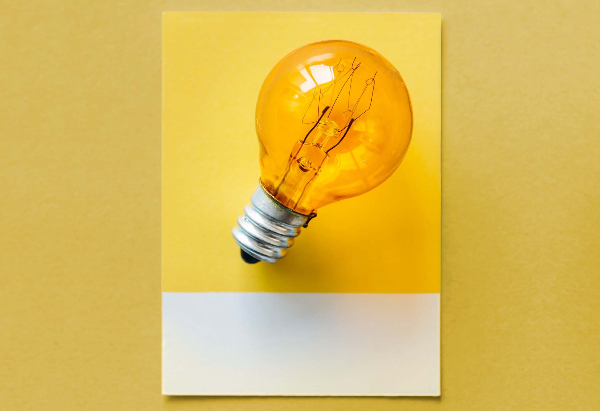 Orange light bulb on a yellow background representing thinking and innovation