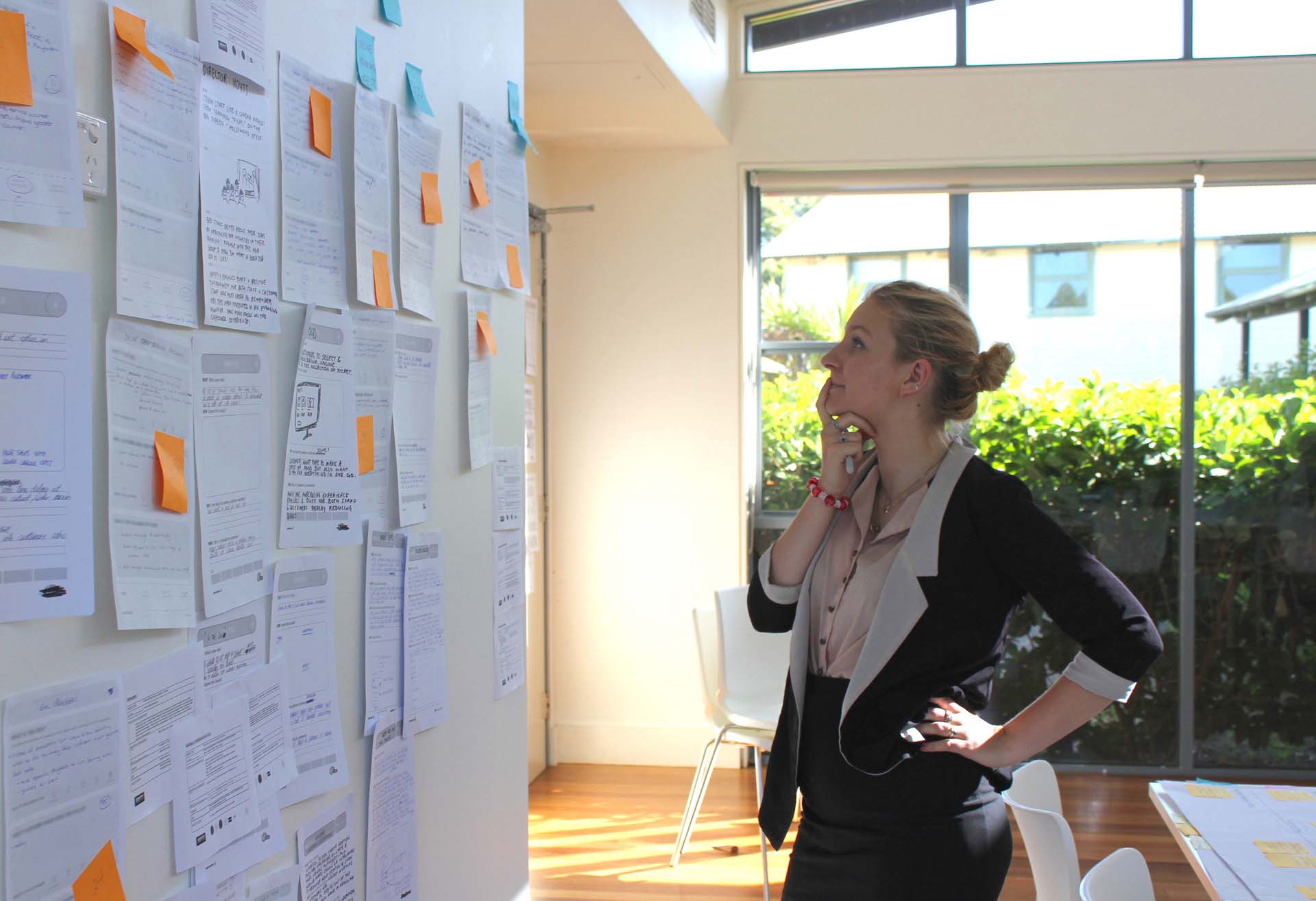 Woman thinking about a wall of Service Design information