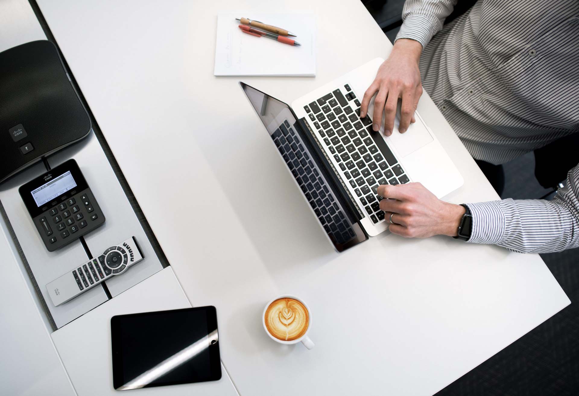 Overhead image of a desk and hands typing on a laptop