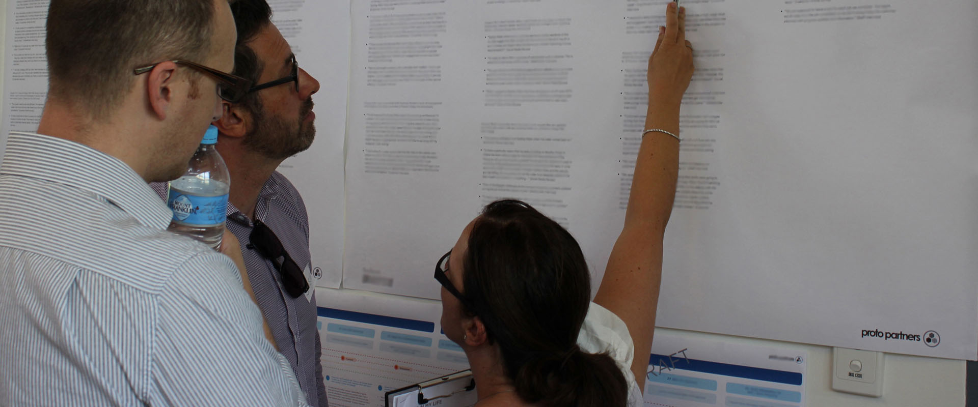 Proto experience designer pointing out CX information to two other designers