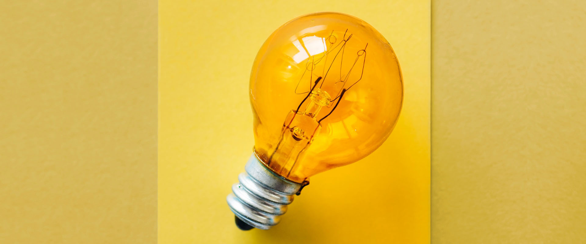 Orange light bulb on a yellow background representing thinking and innovation