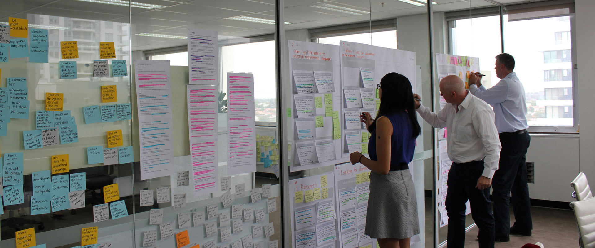 Three Proto employees making notes on a large Customer Journey Map