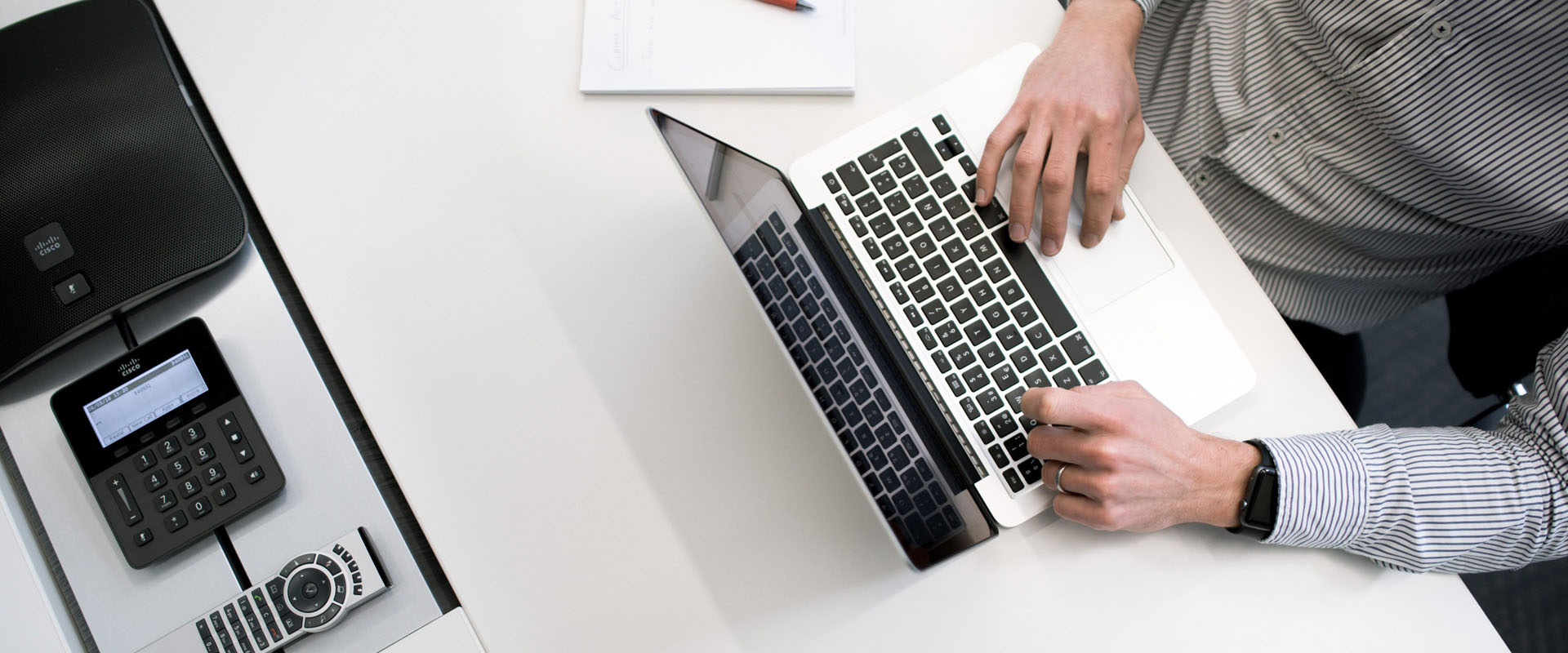 Overhead image of a desk and hands typing on a laptop