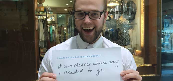 NSW commuter holding up an idea card about his desired improvements saying, I would catch a bus to the train station if it was clear which way I needed to go