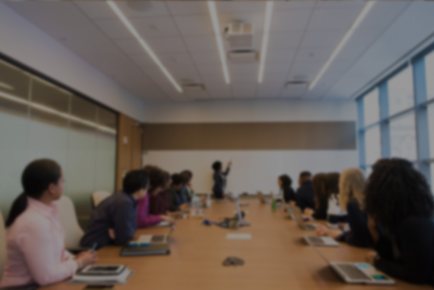 Seated team in a boardroom facing a presenter at the head of the table